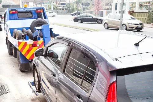 Tow truck towing a broken-down car on the street